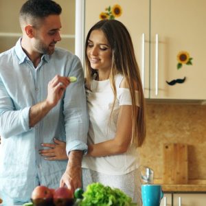 Happy young couple in the kitchen. Handsome man meet and feed his girlfriend early morning at home